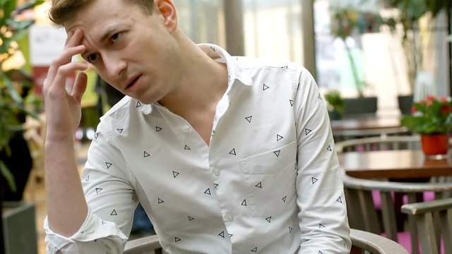 Man sitting in the cafe and having problems with his stomach, steadycam shot
