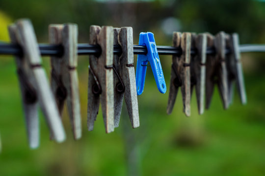 On the wire hang an old wooden clothes pin. Between them there are new plastic clothespins for linen.
