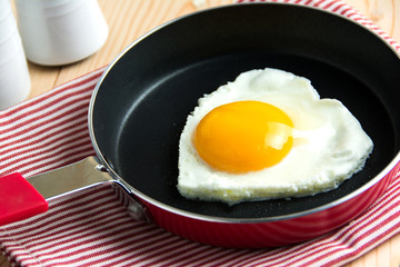 Fried egg in heart shape on a pan