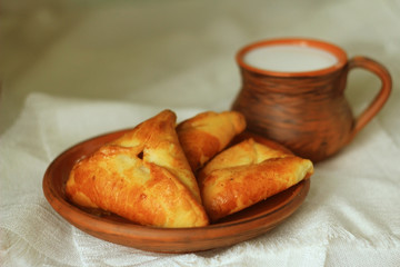  delicious homemade cakes and cup of milk on a table with a white linen cloth