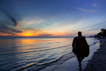 Buddhist monks walk collecting alms, morning beach.