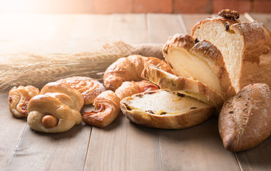 Assortment of baked bread and wheat on wood table