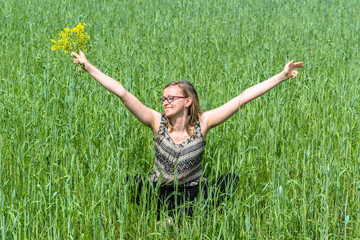 Naklejka na ściany i meble Happy woman with flowers on summer field