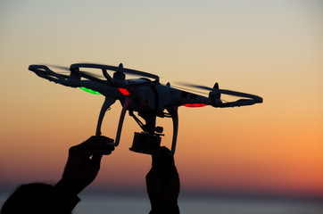 Flying drone with camera on the sky at sunset