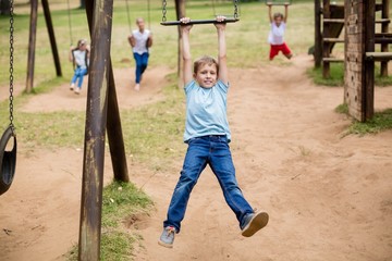 Fototapeta na wymiar Boy hanging on a playing equipment in park