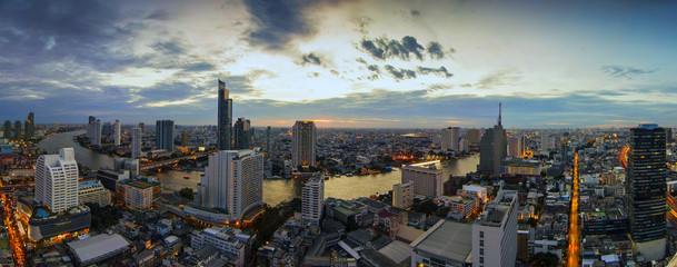 Curve of River and river side view. In a main business zone of Bangkok. It's combining a contrast of shining buildings and blackening living houses. With a colorful twilight sky.