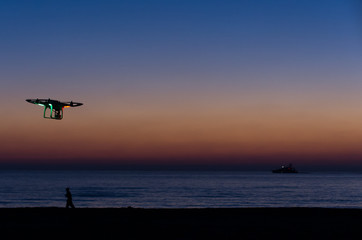 Naklejka na ściany i meble Flying drone with camera on the sky at sunset