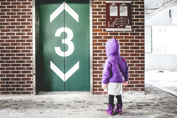 Girl in purple coat at elevator doors 