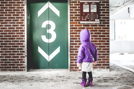 Girl in purple coat at elevator doors 