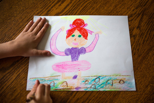 Childs hands drawing ballerina on paper 