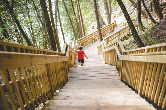 Young boy wearing red t-shirt, descending wooden stairs 