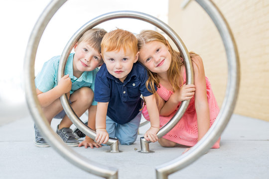 Portrait of happy children looking through steel frame