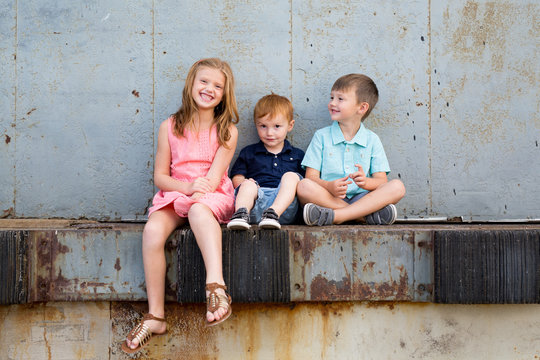 Happy children sitting on ledge together