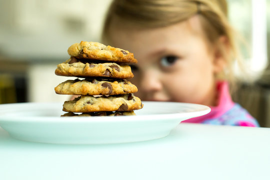 Pile of chocolate chip cookies, child looking behind 