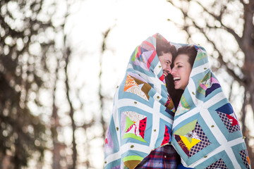 Couple wrapped in patchwork quilt, laughing