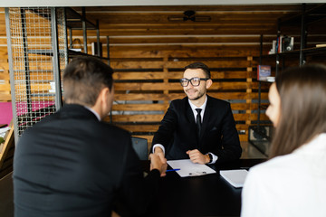 Sell concept. Manager greetings with  couple at his office.