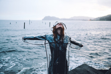 Young woman with arms outstretched standing by the sea