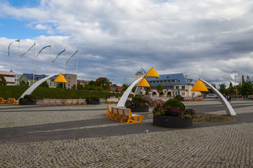 City square with pavement, greenery and modern yellow lanterns