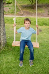 Happy boy sitting on a swing in park