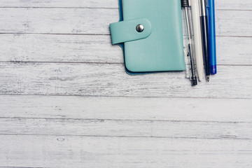 wooden background, blue card holder and pens