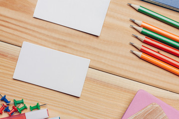 Obraz premium pencils of different colors, buttons and business cards on a wooden background