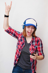 Hands with gesture Horns. That rocks. rock hand sign. Hipster girl style posing, smiling and looks into your smartphone. Swag style on a white background. girl hipster giving the Rock and Roll sign.