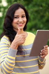 Happy young woman holding tablet computer at outdoor