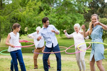Multi-generation family playing with hula hoop - obrazy, fototapety, plakaty