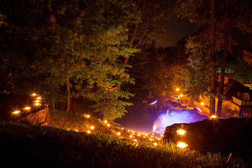 River from candles, "Day of light" show in European town. Summer night in city park