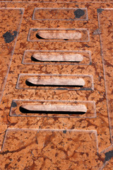 Water drain in red marble with four holes. Italian pedestrian street
