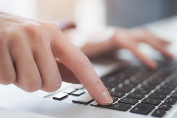 closeup of a human finger pressing the enter key on a keyboard