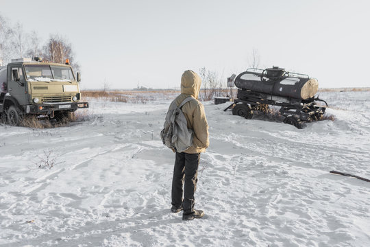 errant young boy in winter post-apocalyptic world. a homeless boy. boy in a protective jacket with a hood. teenager standing in the midst of abandoned cars. nuclear winter. Apocalypse