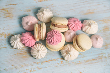 Macaroons and meringues on baby blue wooden background flat lay. Top view. french sweets.   