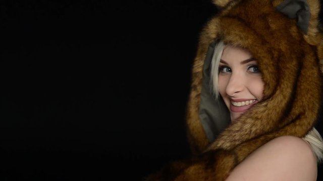 sexy woman posing in front of the camera without a bra in a fur hat on a black background