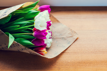 the bouquet of tulips is wrapped in a paper isolated on a wood b