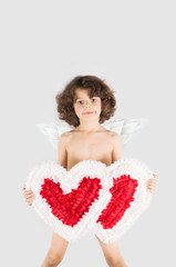 Cute curly angel standing, holding two hearts, looking into the camera. White background.