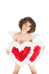Young curly angel standing head bowed, holding two hearts, looking into the camera. White background.