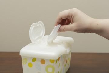 a female hand pulling a baby wipe from a box