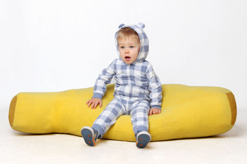 Portrait of an adorable baby boy sitting on the yellow bean bag.


