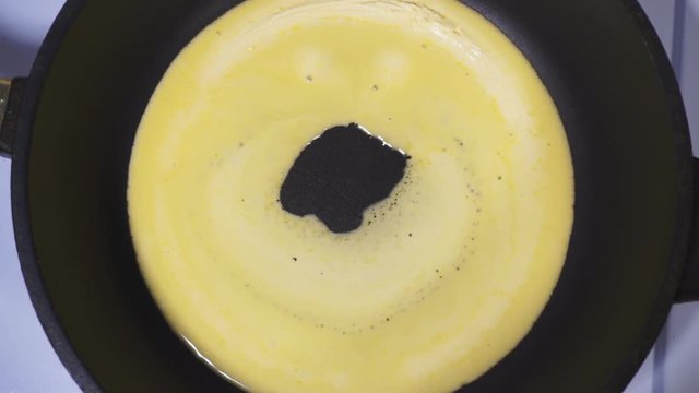 Emoticon made from butter, reverse video. Smiley is melted in a skillet.