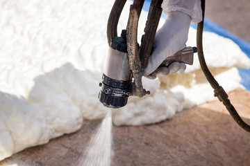 Technician spraying foam insulation using Plural Component Spray Gun - obrazy, fototapety, plakaty