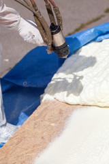 Technician spraying foam insulation using Plural Component Spray Gun