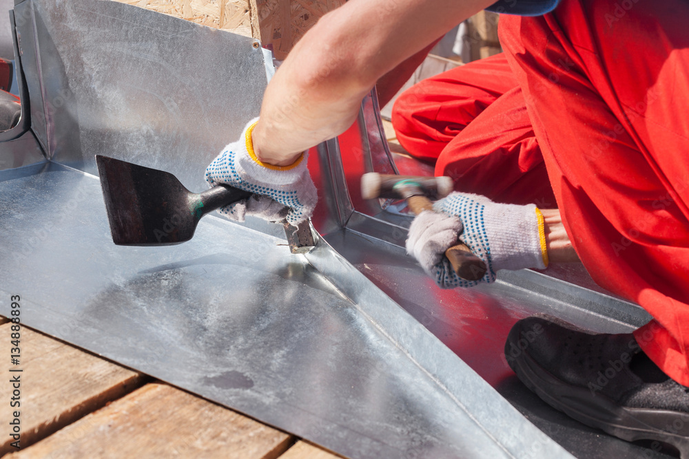 Wall mural roofer builder worker finishing folding a metal sheet using rubber mallet