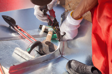 Roofer builder worker finishing folding a metal sheet using metal shears