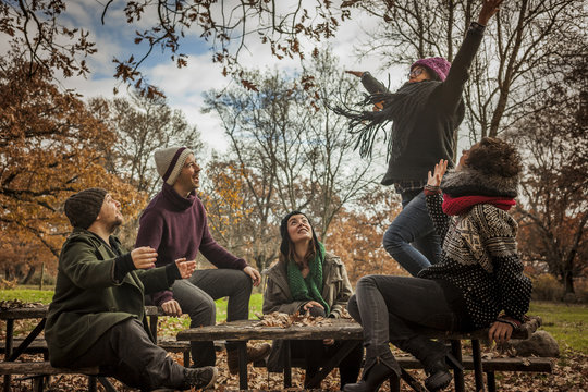 Woman with friends throwing up leaves in the park