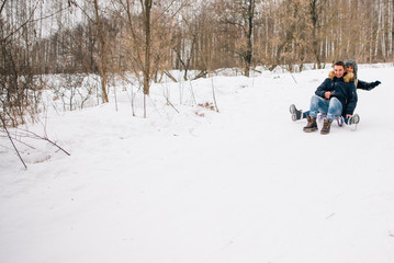 beautiful young couple riding the mountain on a sled. winter love story