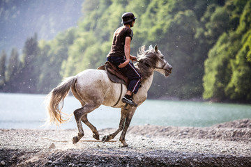 rider galloping on horseback along the river Bank - Powered by Adobe