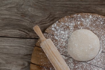 Rolling pin with pizza dough and flour on rolling board