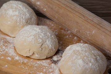Fototapeta na wymiar Rolling pin with pizza dough and flour on chopping board