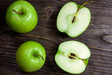 ripe green apples and apple slices on wooden gray background